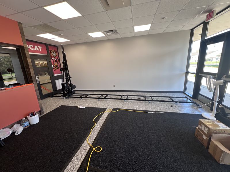 Behind the scenes: the WallPrint wall printer and floor track set up in front of the blank wall before printing